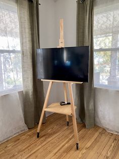 an easel stands in front of a large screen tv on a wooden tripod