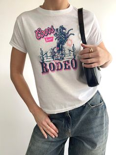 Beer Rodeo 90s Baby Tee, Coors Cowboys tshirt 90's YOUTH baby tee style tshirts! These are YOUTH TEES for the classic 90s baby tee look! Hi! If you have any questions or want to make changes to your order, please message me. ⭐HOW TO ORDER - Please Choose the SIZE and COLOR From Drop Down Menu. ⭐MATERIAL - Cotton Polyester blend fabrics with direct to garment process. Everything is made in house. ⭐SHIPPING - Processing times can verify, dark color shirts do take longer to make, it should take abo Vintage Summer T-shirt For Rodeo, Trendy Relaxed Fit T-shirt For Rodeo, White Graphic Tee For Rodeo, White Crew Neck T-shirt For Rodeo, Graphic Tee For Rodeo And Spring, Spring Graphic Tee For Rodeo, Spring Rodeo Graphic Tee, White Graphic Print Top For Rodeo, Retro Summer T-shirt For Rodeo