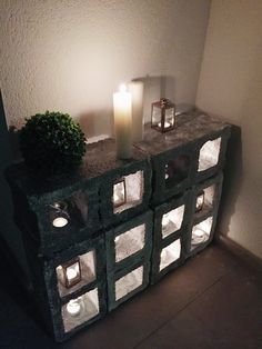 some candles are sitting on top of a small cabinet with glass blocks in front of it