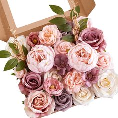 a bouquet of pink and purple flowers in a cardboard box with greenery on top