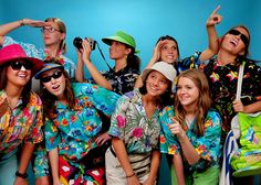 a group of people in colorful shirts and hats posing for a photo with one person holding a camera