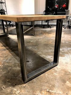 a wooden table sitting on top of a cement floor next to a metal framed mirror