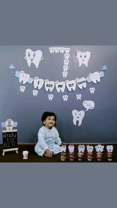 a little boy sitting on the floor in front of toothpaste cutouts that spell out teeth