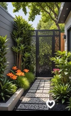 an outdoor garden with plants and flowers on the side of a house in front of a gate