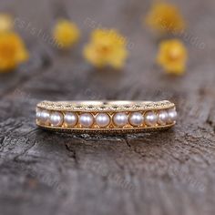 a close up of a ring on a wooden surface with yellow flowers in the background