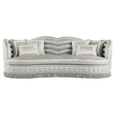 a couch with pillows and fringe trims on the back, sitting in front of a white background