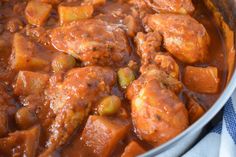 a pot filled with meat and vegetables on top of a blue checkered table cloth