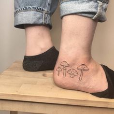 a person's foot with mushroom tattoos on the bottom of their ankles and feet