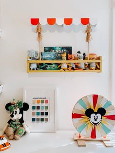 there is a mickey mouse and other items on the shelf in this room, including a fan