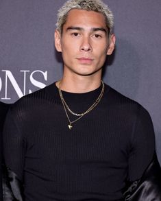 a man with grey hair wearing a black shirt and gold chain necklace on his neck