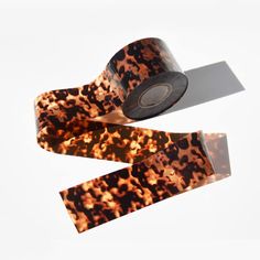 two rolls of brown and black leopard print tape sitting on top of each other,