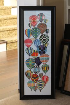 an art piece with hot air balloons on it next to a framed photo and other items