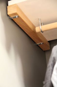 a close up of a wooden shelf with clothes hanging from it's sides and a coat rack attached to the wall