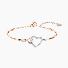 This heart bracelet combines the precision and quality of sparkling crystals with a chic rhodium plated chain, making this endearing look a cute accessory. A single white crystal adorns a dainty infinity sign interlaced with a dazzling white crystal pave heart, adding a brilliant and romantic touch to the simple, refined design. Rose Gold Metal Heart Bangle Bracelet, Rose Gold Heart Bangle Bracelet, Rose Gold Metal Heart Bangle, Heart-shaped Rose Gold Bracelets For Party, Rose Gold Heart Bracelets For Party, Elegant Metal Chain Bracelet For Valentine's Day, Elegant Metal Heart Bracelet For Party, Elegant Rose Gold Crystal Bracelet, Valentine's Day Rose Gold Heart Bangle Bracelet