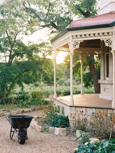 a wheelbarrow in front of a gazebo with trees and bushes around it