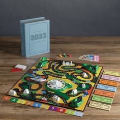 a board game sitting on top of a wooden table next to a book and some cards