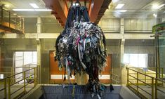 a large sculpture made out of clothes hanging from the ceiling in a room with metal railings