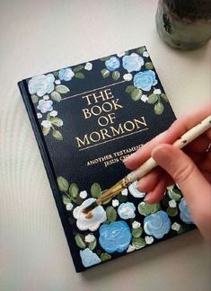 the book of mormon is being held by a person's hand with a pen