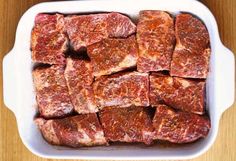 raw meat in a white casserole dish on a wooden table