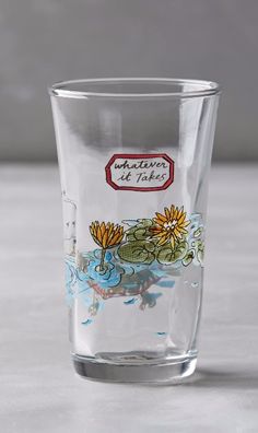 a shot glass sitting on top of a table with water and flowers painted on it