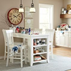 a white table and chairs in a room with a clock on the wall behind it