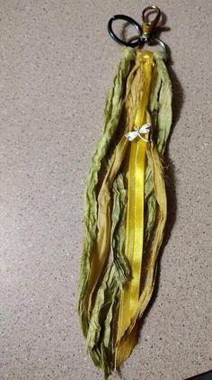 a piece of fabric with yellow ribbon hanging from it's end on the floor