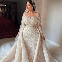 a woman in a wedding dress posing for the camera with her veil draped over her head