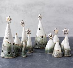 seven ceramic christmas trees are lined up on a table