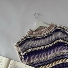 an open book is next to a crocheted sweater