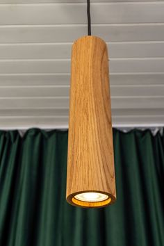 a wooden light hanging from a ceiling in front of green curtained walls and drapes