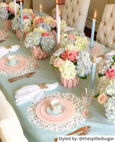 the table is set with pink and white flowers in vases, plates, napkins, silverware, and candles