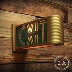 a green and gold clock mounted to the side of a wooden wall next to a light