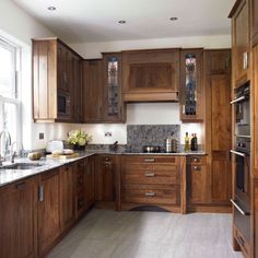 a kitchen with wooden cabinets and marble counter tops