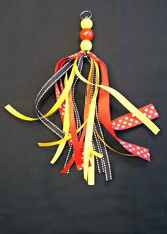 an ornament made out of ribbon on a black background with red, yellow and white polka dots