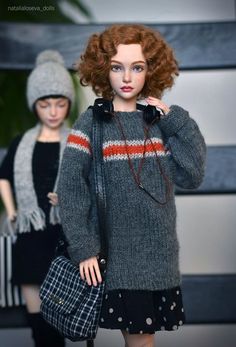 a doll with red hair is holding a handbag and wearing a gray knitted sweater