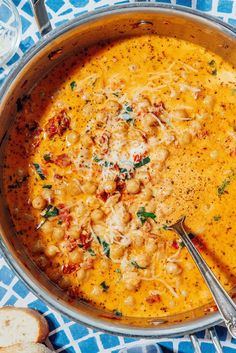 a pot filled with pasta and cheese on top of a blue table cloth next to bread