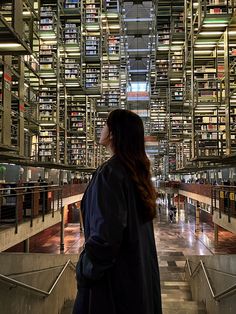 a woman standing in front of a library filled with books