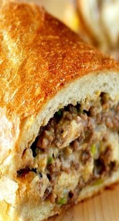 a close up of a sandwich on a wooden table with other food items in the background