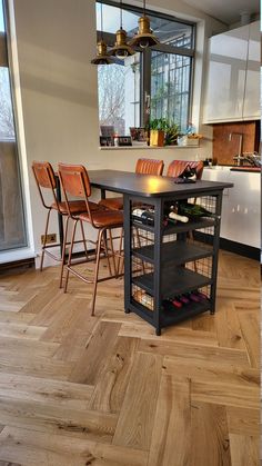 a kitchen with wooden floors and an island in the middle that has several chairs around it