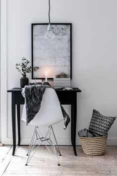 a white chair sitting next to a table with a painting on the wall above it