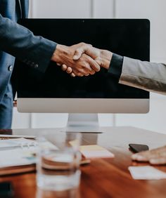 two people shaking hands over a computer screen