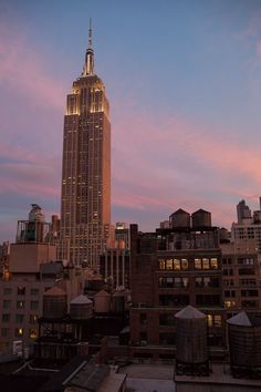 the empire building is lit up at night in new york city, ny on a pink and blue sky