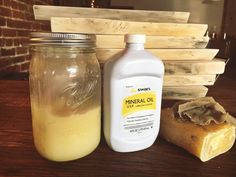 a bottle of vinegar next to a soap bar on a wooden table with wood planks in the background