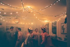 a group of people standing around each other in a room with lights on the ceiling