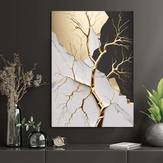 a white and gold painting on the wall next to a vase with plants in it