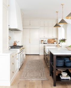 a kitchen with white cabinets and blue plates on the counter top, along with an area rug