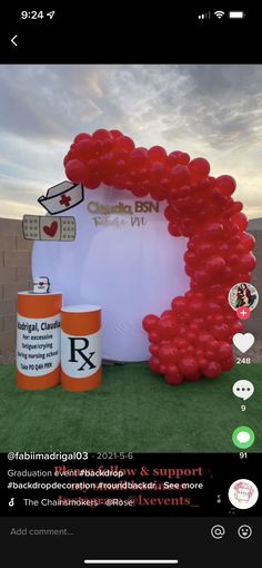 the balloon arch is decorated with red heart balloons and an orange canister next to it