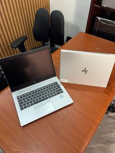 an open laptop computer sitting on top of a wooden table next to a white box