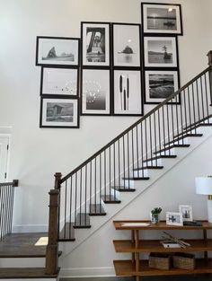 a staircase with pictures on the wall above it and a table under it in front of some stairs