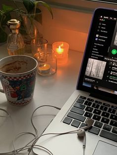 an open laptop computer sitting on top of a white desk next to a cup of coffee